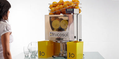 Frucosol F50C Juicer full of oranges and a person is walking up to the unit.