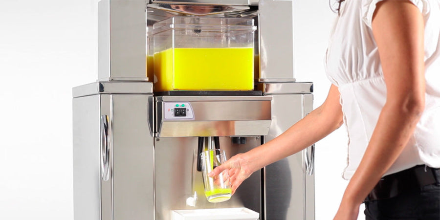 Frucosol Freezer Automatic Juicer, a person filling a glass of juice from the unit.