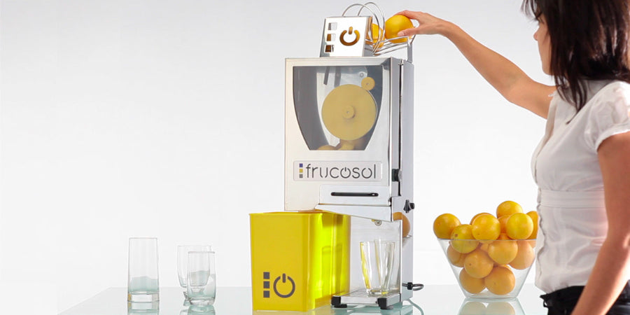 A person putting an orange into the top of the Frucosol F-Compact Juicer