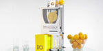Frucosol F-Compact Juicer with a bowl of oranges to the right side of the unit and a glass under the unit about to be filled with freshly extracted orange juice.
