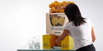 Person operating a Frucosol F50 Juicer, filling their glass with orange juice.