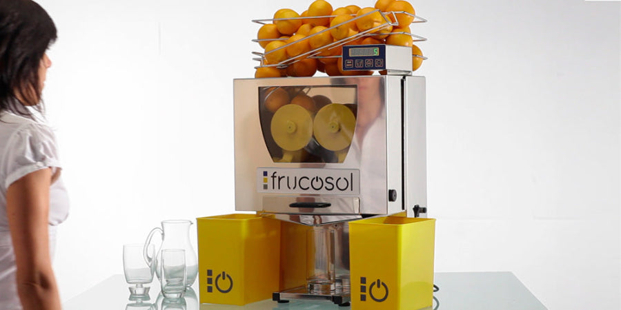 Frucosol F50C Juicer full of oranges and a person is walking up to the unit.