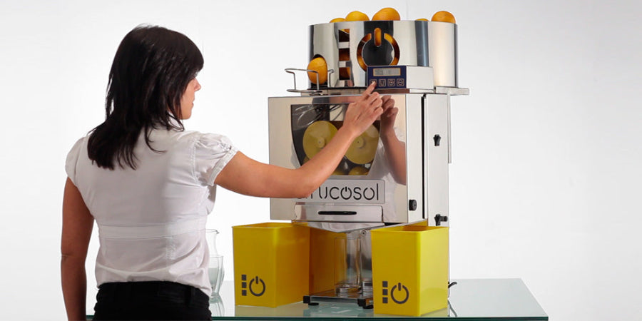 Person using a Frucosol F50AC Juicer full of oranges on a white background
